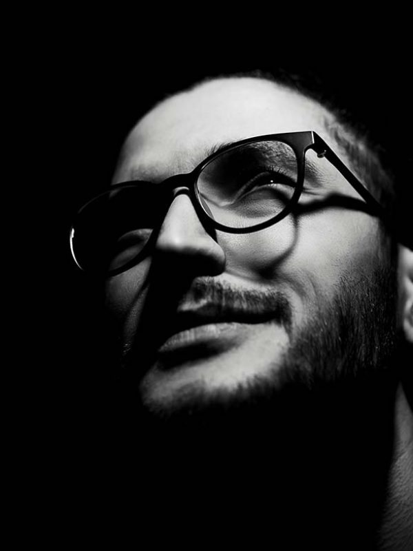 black-white-closeup-dark-portrait-young-smiling-man-wearing-glasses